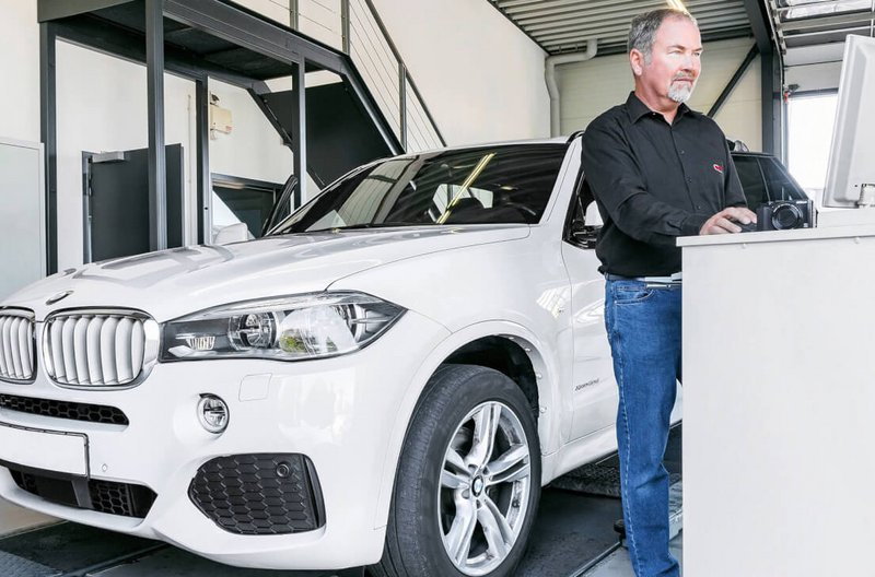 Leasing Rückläuferprüfung Ein Mitarbeiter von GTÜ Neidhardt steht an einem Prüfstand und bedient einen Computer, vor ihm steht ein weißes Auto.
