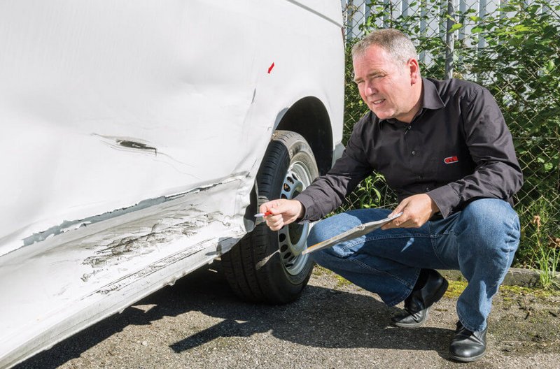Schadensgutachten bei GTÜ Neidhardt Ein Mitarbeiter von GTÜ Neidhardt erstellt ein Schadensgutachten an einem weißen Auto nach einem Unfall.